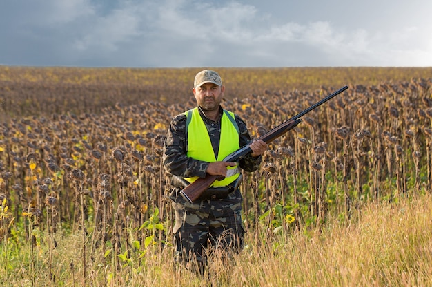 Silhouette of a hunter with a gun in the reeds against the sun, an ambush for ducks with dogs