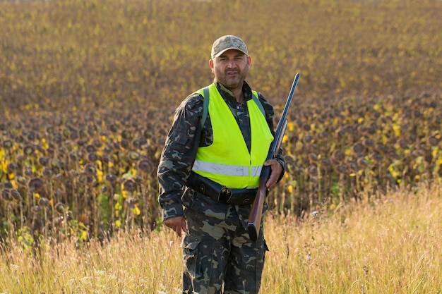 Silhouette of a hunter with a gun in the reeds against the sun, an ambush for ducks with dogs