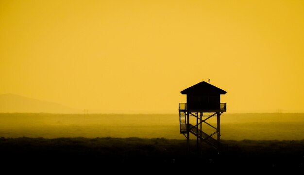 Silhouette hut on tower against sky during sunset