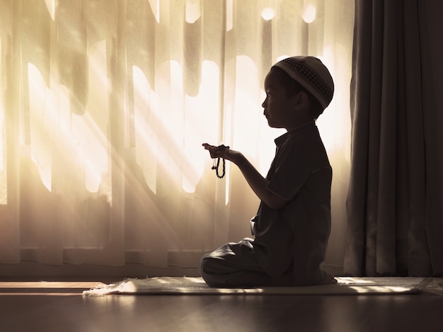 Photo silhouette image of muslim pre school kid pray to god (doing  dua or supplication).concept of muslim kid praying.