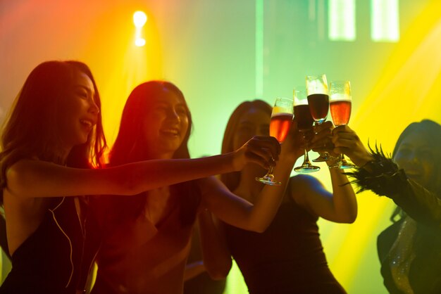 Silhouette image of people dance in disco night club to music from DJ on stage