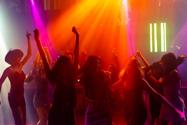 디스코 나이트 클럽에서 무대에서 DJ의 음악에 맞춰 춤을 추는 사람들의 실루엣 이미지