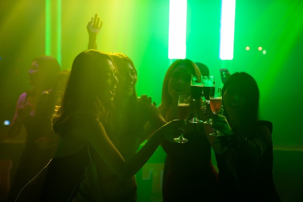 Silhouette image of people dance in disco night club to music from DJ on stage