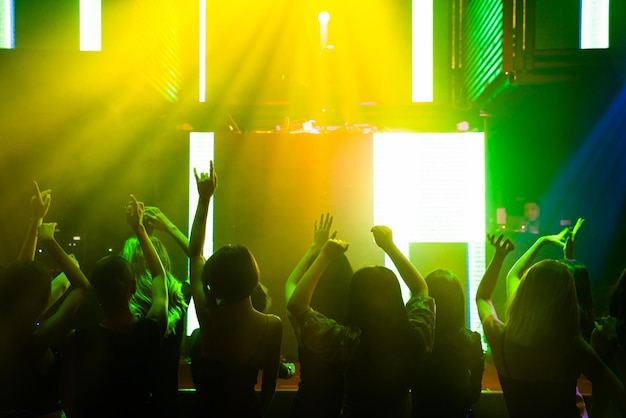 Силуэт изображения людей танцуют в ночном клубе диско под музыку от ди-джея на сцене