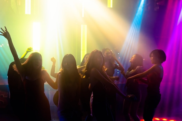 Silhouette image of people dance in disco night club to music\
from dj on stage