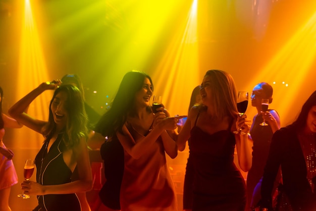 Silhouette image of people dance in disco night club to music from DJ on stage