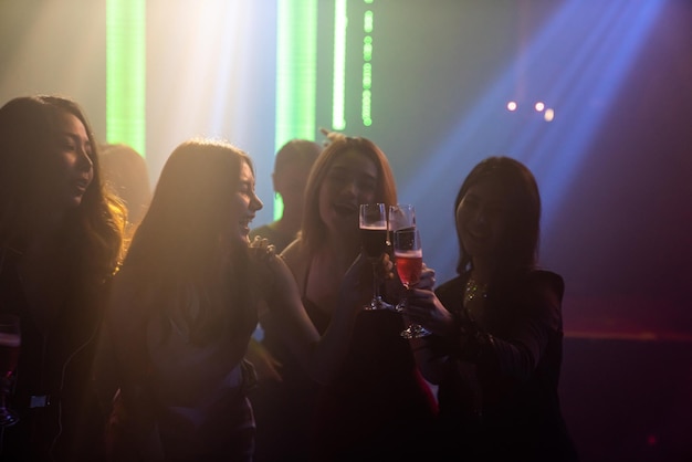 Silhouette image of people dance in disco night club to music\
from dj on stage