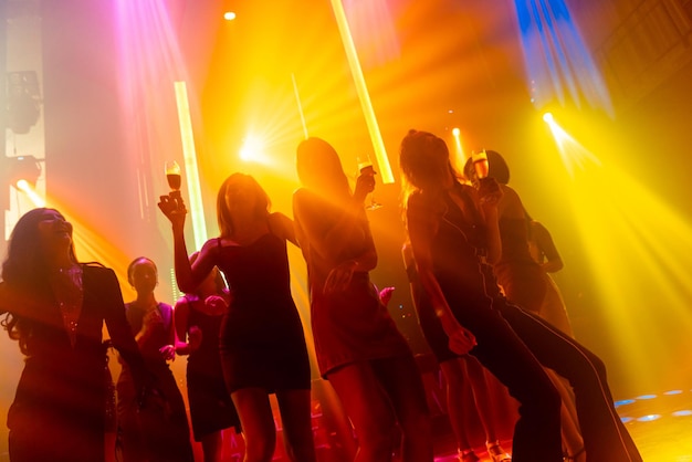 Silhouette image of people dance in disco night club to music\
from dj on stage