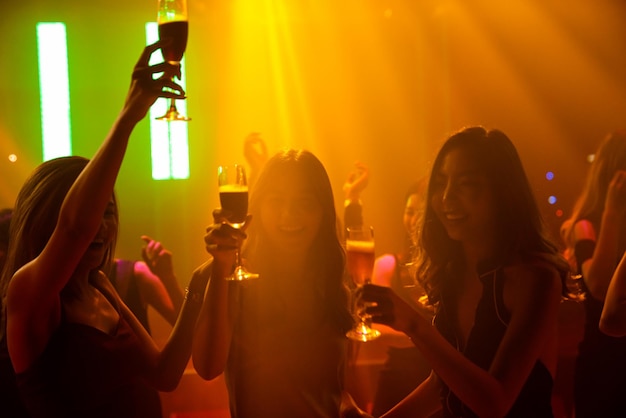 Silhouette image of people dance in disco night club to music from DJ on stage