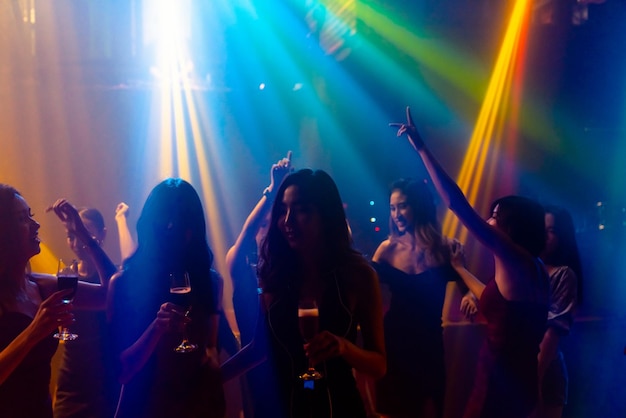 Silhouette image of people dance in disco night club to music\
from dj on stage