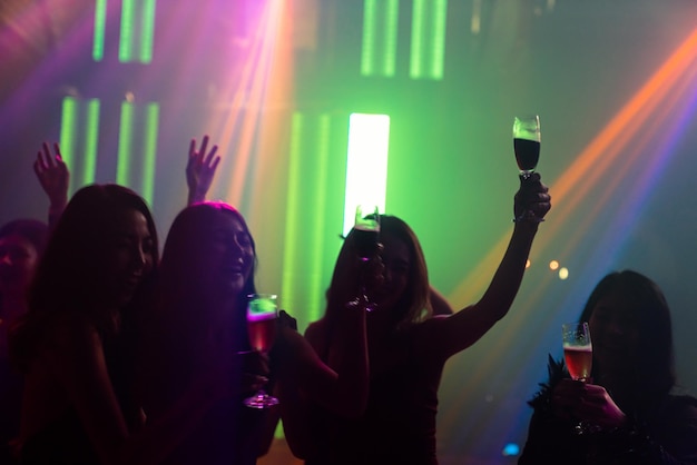 Silhouette image of people dance in disco night club to music\
from dj on stage