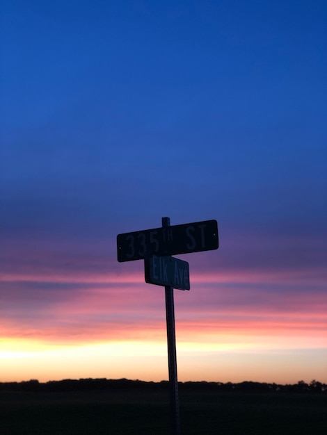 Silhouette information sign against sky at sunset