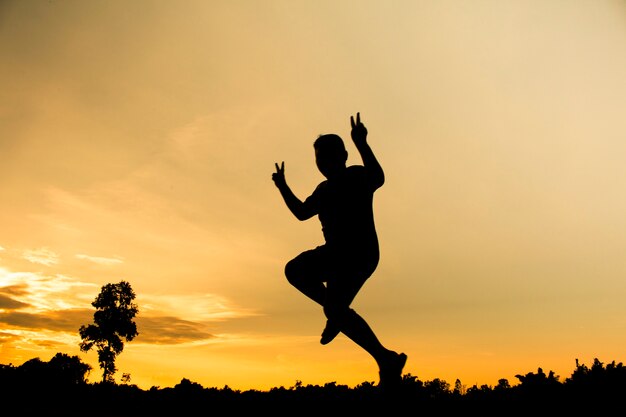 Silhouette of a jumper is jumping with beautiful sunset background