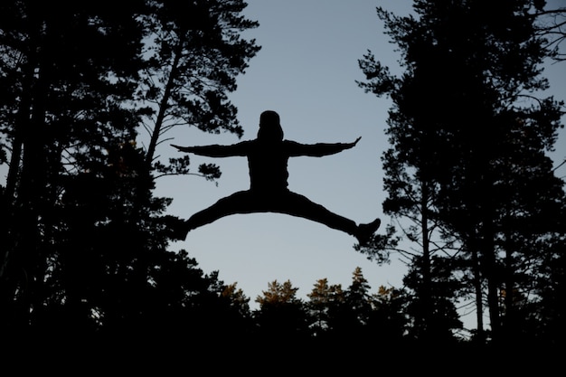 Silhouette jumping man against blue sky.