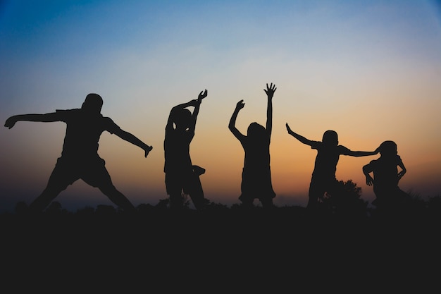 Silhouette di bambini che corrono e godono in mezzo al campo di riso al tramonto