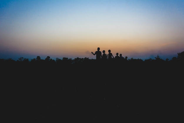 silhouette of kids running and playing in midst of rice field at sunset