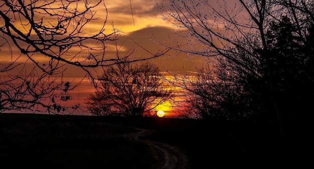 silhouette of landscape against cloudy sky at sunset