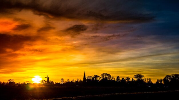 Silhouette landscape against dramatic sky during sunset