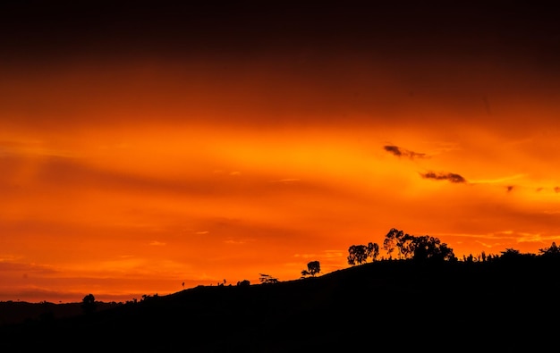 Silhouette landscape against dramatic sky during sunset