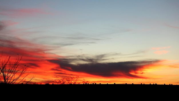 Silhouette landscape against orange sky during sunset