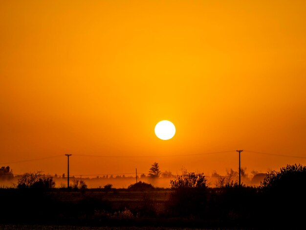 Silhouette landscape against orange sky during sunset