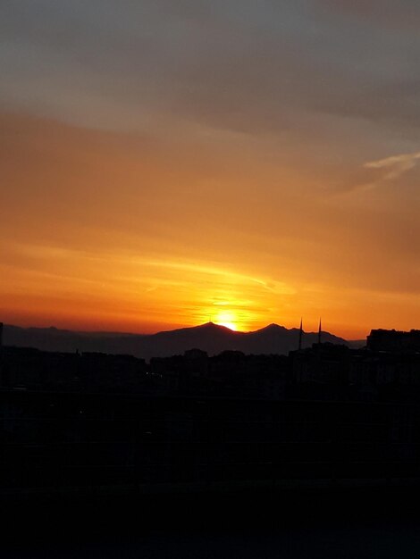 Silhouette landscape against orange sky