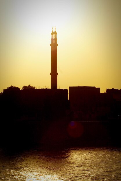 写真 夕暮れの空を背景に川の灯台のシルエット