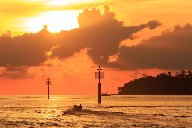 Silhouette lighthouse by sea against sky during sunset