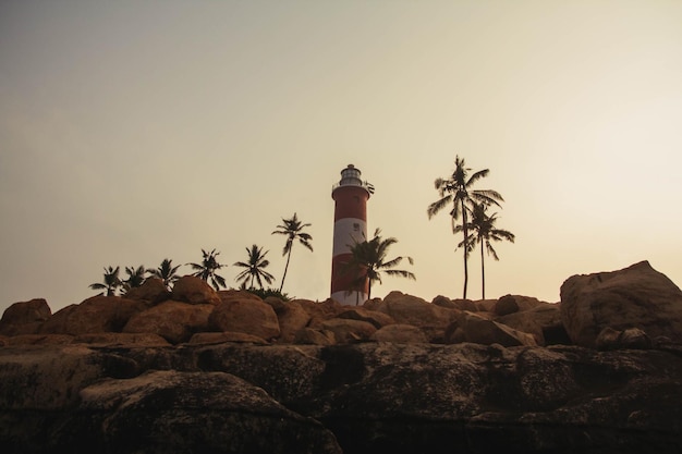 Silhouette of a lighthouse and palms trees in Kovalam Kerala India Copy empty space for text