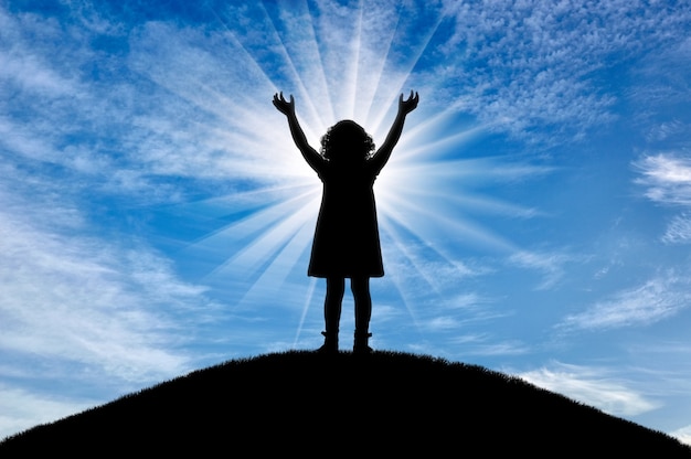 Silhouette, little happy girl child standing on a hill. Conceptual image of childhood