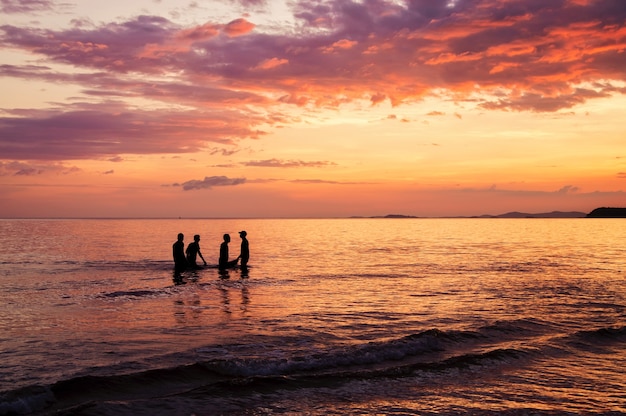 劇的な夕焼けの空と海の地元の漁師のシルエット