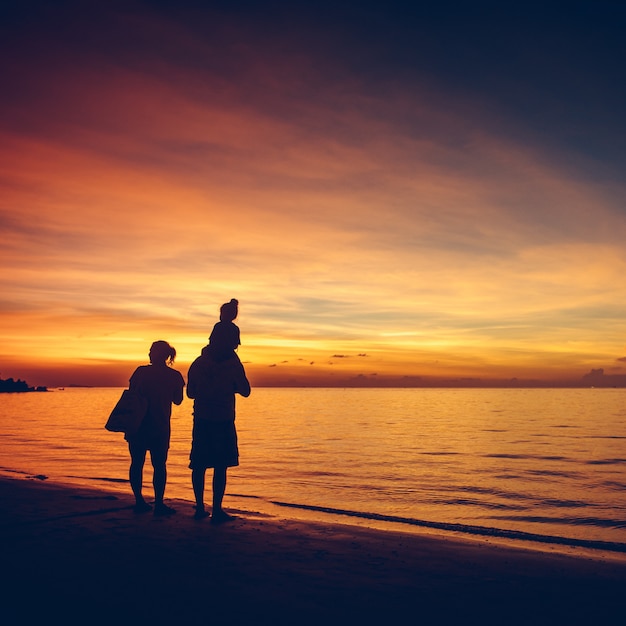 Silhouette of lovely family on the sunset beach