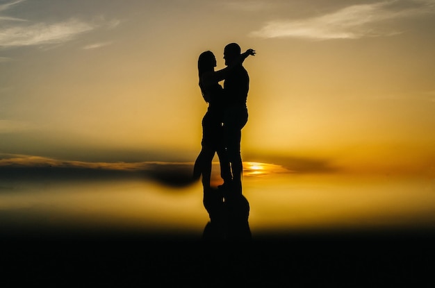 silhouette of a loving couple embracing at sunset