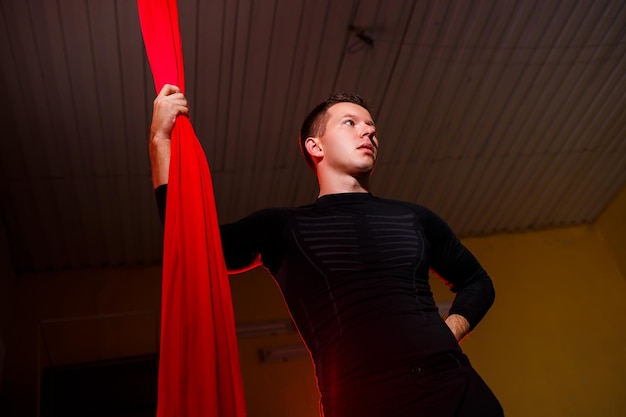Il ginnasta aereo maschio della siluetta si esibisce su tele rosse
