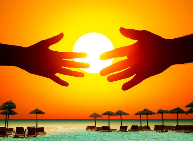 silhouette of male and female hands against the backdrop of the setting sun at an ocean resort