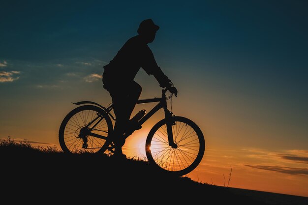 Silhouette of a male mountainbiker at sunset in the mountains The idea and concept of a healthy lifestyle outdoor activities and sports