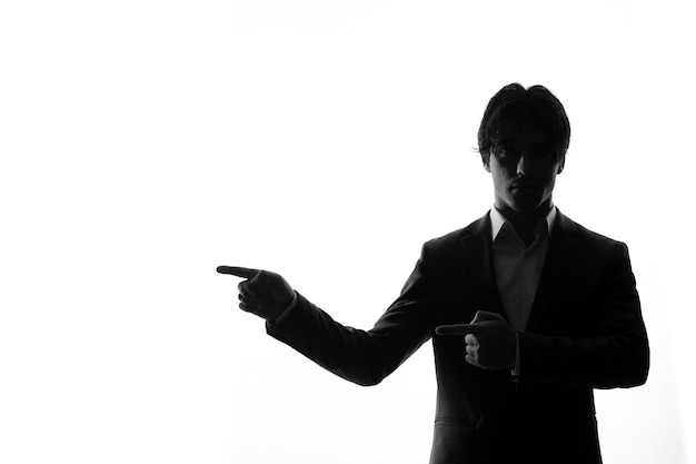 Silhouette of male in strict suit pointing at something shadow back lit white background