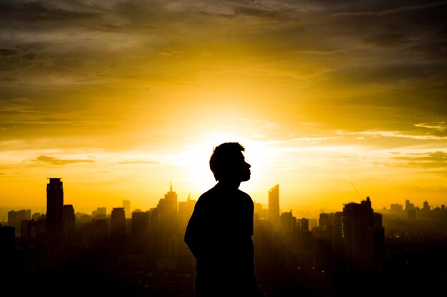 Silhouette man against cityscape during sunset