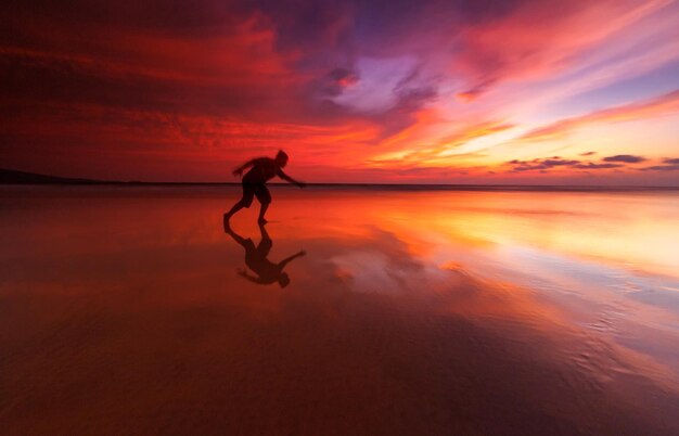 Silhouette man on beach against sky during sunset