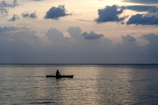 海に沈む夕日のボートに乗って男のシルエット