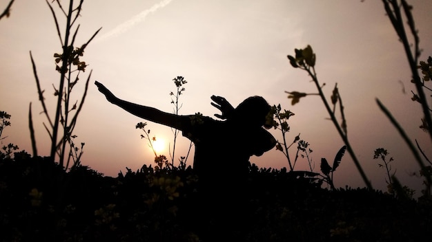 Foto silhouette uomo dabbing mentre in piedi sul campo contro il cielo durante il tramonto