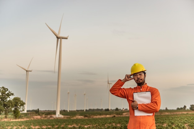 MountainThailandの人々の風力タービンファーム発電機ステーションで作業し、レポートを保持している男性エンジニアのシルエット