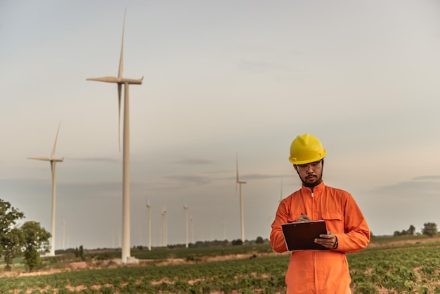 MountainThailandの人々の風力タービンファーム発電機ステーションで作業し、レポートを保持している男性エンジニアのシルエット