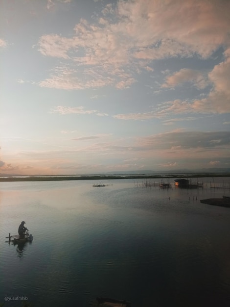 午後に釣りをする男性のシルエット。リンボト湖、インドネシアの夕日