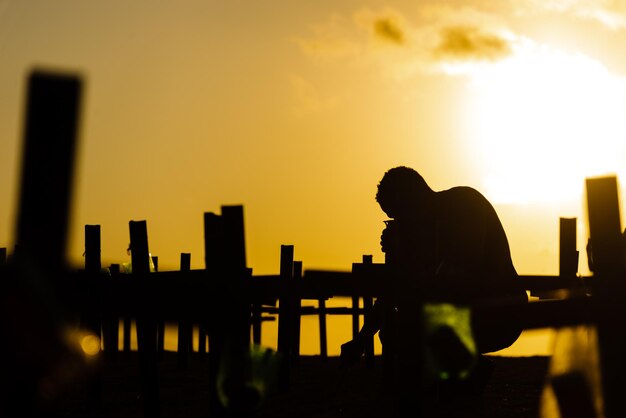 Silhouette of a man fixing crosses on the ground in honor of\
those killed by covid19