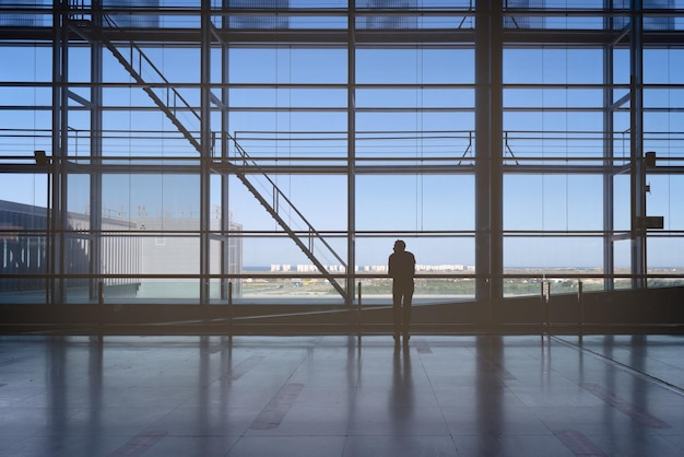 Photo silhouette of man in front of windows of the airport terminal