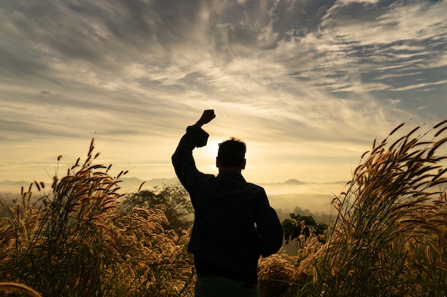 写真 シルエット男幸せな手で立っている日の出の空と山の上に立ち上がる。