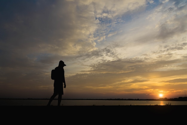 Siluetta di un uomo felice che cammina al tramonto.