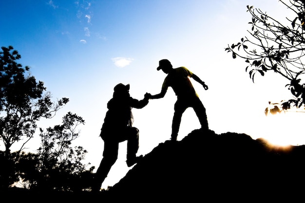 Silhouette of man hold up hands on the peak of mountainsuccess concept