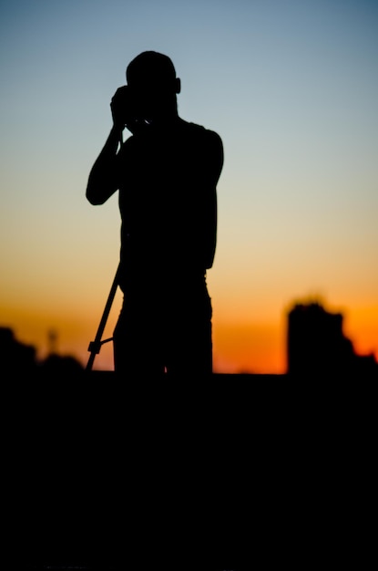 Фото Силуэт человека с камерой и стоящего на небе во время захода солнца